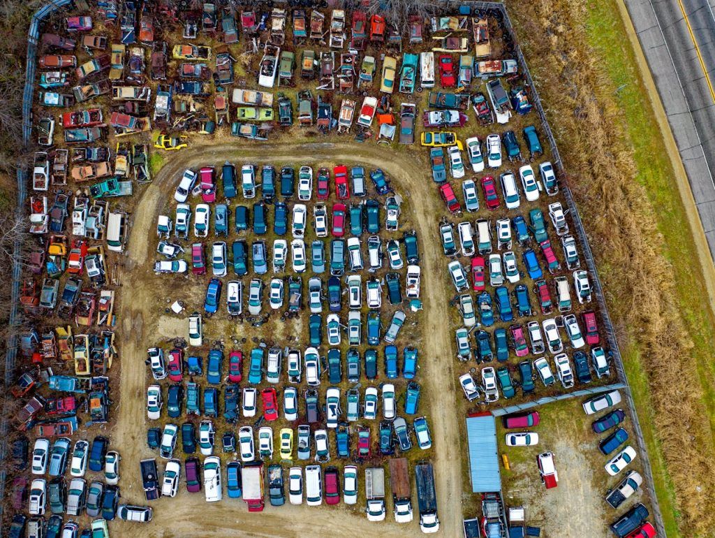 Drone view of a sprawling car junkyard with vintage vehicles in Rochester, MN.